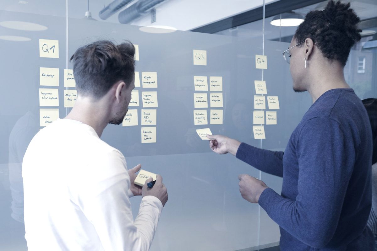 A team mapping out a workflow with sticky notes on glass.